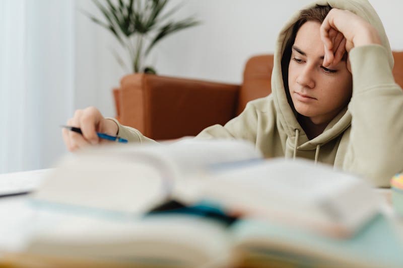 Teenager studying with books at home