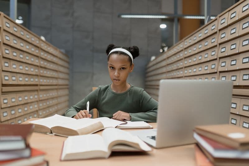 Student reading in a library aisle